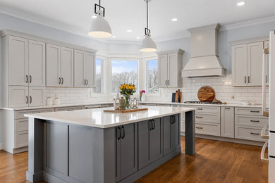 Eat-in kitchen - large transitional u-shaped medium tone wood floor, brown floor and vaulted ceiling eat-in kitchen idea in Detroit with an undermount sink, shaker cabinets, white cabinets, quartz countertops, white backsplash, ceramic backsplash, white appliances, an island and white countertops