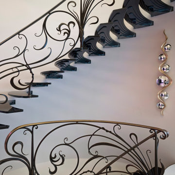 Amazing floating staircase with cantileverd glass treads and artistic balustrade