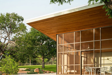 Mid-sized mid-century modern one-story stucco house exterior idea in Austin with a metal roof