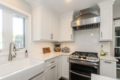 Mid-sized transitional u-shaped medium tone wood floor and brown floor eat-in kitchen photo in Chicago with a farmhouse sink, shaker cabinets, white cabinets, quartzite countertops, white backsplash, porcelain backsplash, stainless steel appliances, an island and white countertops