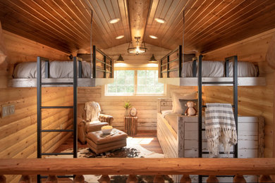This is an example of a medium sized rustic kids' bedroom in Other with brown walls, medium hardwood flooring, brown floors, a vaulted ceiling and wood walls.