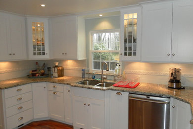 Mid-sized elegant u-shaped medium tone wood floor and brown floor enclosed kitchen photo in Providence with a double-bowl sink, shaker cabinets, white cabinets, granite countertops, white backsplash, subway tile backsplash, stainless steel appliances, no island and multicolored countertops