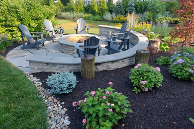 Ejemplo de jardín de estilo de casa de campo de tamaño medio en patio trasero con brasero, exposición total al sol y adoquines de piedra natural