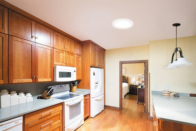 Mid-sized trendy single-wall light wood floor eat-in kitchen photo in Austin with flat-panel cabinets, brown cabinets, laminate countertops, white appliances and an island