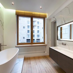 Создайте стильный интерьер: ванная комната в современном стиле с плоскими фасадами, коричневыми фасадами, отдельно стоящей ванной, белыми стенами, светлым паркетным полом, монолитной раковиной, бежевым полом и белой столешницей - последний тренд