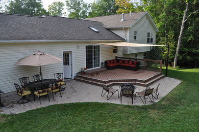 This is an example of a mid-sized traditional partial sun backyard stone landscaping in New York with a fire pit.