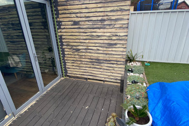This is an example of a mid-sized contemporary backyard and ground level deck in Melbourne with with privacy feature and no cover.