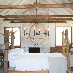 Großes Rustikales Hauptschlafzimmer mit weißer Wandfarbe, hellem Holzboden, Kamin, Kaminumrandung aus Backstein und grauem Boden in Sonstige