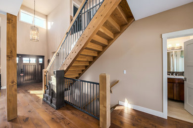 Example of an arts and crafts medium tone wood floor entryway design in Calgary with beige walls and a dark wood front door