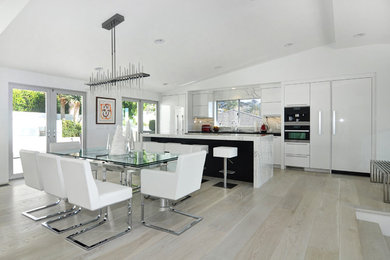 This is an example of a mid-sized contemporary kitchen/dining combo in Orange County with white walls and light hardwood floors.
