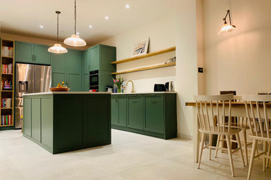 ロンドンにある高級な広いコンテンポラリースタイルのおしゃれなキッチン (シングルシンク、シェーカースタイル扉のキャビネット、緑のキャビネット、御影石カウンター、白いキッチンパネル、御影石のキッチンパネル、黒い調理設備、磁器タイルの床、白い床、白いキッチンカウンター) の写真