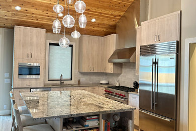 Kitchen photo in Other with granite countertops, white backsplash, stainless steel appliances and an island