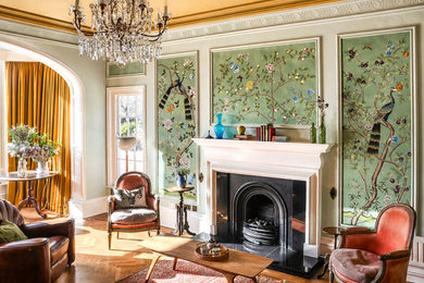Large bohemian formal enclosed living room feature wall in Other with green walls, medium hardwood flooring, a wooden fireplace surround, no tv, brown floors and wallpapered walls.