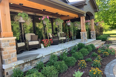 This is an example of a large craftsman stone front porch design in Omaha.