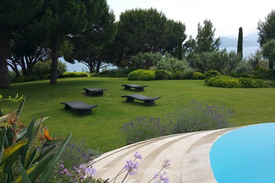 На фото: большой солнечный, весенний регулярный сад на заднем дворе в средиземноморском стиле с хорошей освещенностью