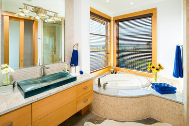 Trendy beige tile and mosaic tile corner bathtub photo in Other with a vessel sink, flat-panel cabinets and light wood cabinets