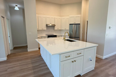 Inspiration for a mid-sized contemporary laminate floor and beige floor kitchen remodel in Other with an undermount sink, shaker cabinets, white cabinets, quartz countertops, white backsplash, cement tile backsplash, stainless steel appliances, an island and white countertops