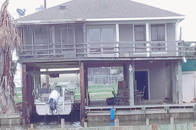 Mid-sized coastal one-story concrete fiberboard and board and batten house exterior idea in Houston with a hip roof, a shingle roof and a gray roof