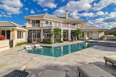 This is an example of a large traditional backyard pool in Miami with natural stone pavers.