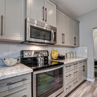 Mid-sized farmhouse kitchen pantry ideas - Example of a mid-sized farmhouse u-shaped medium tone wood floor kitchen pantry design in Calgary with a double-bowl sink, recessed-panel cabinets, gray cabinets, granite countertops, white backsplash, ceramic backsplash, stainless steel appliances and an island