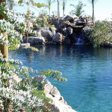 Waterfall leading into a large pool surrounded by imported boulders and native p