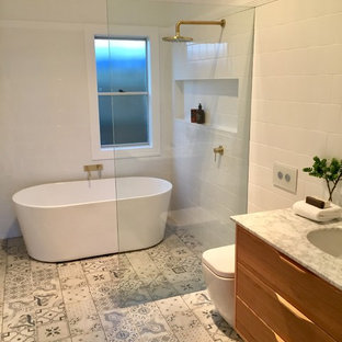 Idées déco pour une salle d'eau moderne de taille moyenne avec un placard en trompe-l'oeil, des portes de placard en bois clair, une baignoire indépendante, une douche ouverte, un WC à poser, un carrelage blanc, des carreaux de céramique, un mur blanc, sol en stratifié, un lavabo encastré, un plan de toilette en marbre, un sol multicolore, aucune cabine et un plan de toilette blanc.