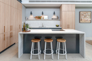 Design ideas for a contemporary l-shaped kitchen in Sydney with flat-panel cabinets, light wood cabinets, white splashback, panelled appliances, with island, white floor and white benchtop.