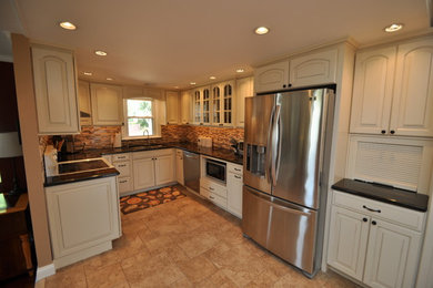 Eat-in kitchen - small traditional u-shaped porcelain tile eat-in kitchen idea in Philadelphia with an undermount sink, raised-panel cabinets, white cabinets, laminate countertops, brown backsplash, glass tile backsplash, stainless steel appliances and no island