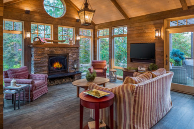 This is an example of a country sunroom in Portland with dark hardwood floors, a standard fireplace, a stone fireplace surround, a standard ceiling and brown floor.