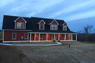 Inspiration pour une grande façade de maison rouge rustique en stuc à un étage avec un toit à deux pans et un toit en shingle.