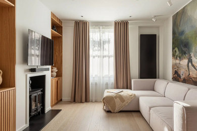 Inspiration for a large scandi formal and grey and cream enclosed living room in London with white walls, light hardwood flooring, a wood burning stove, a metal fireplace surround, a wall mounted tv, beige floors, a drop ceiling and a chimney breast.