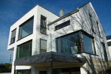 Expansive contemporary three-storey white exterior in Dortmund with stone veneer and a gable roof.
