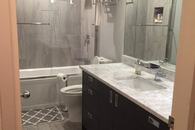 Example of a mid-sized trendy master gray tile, white tile and porcelain tile porcelain tile bathroom design in Austin with flat-panel cabinets, dark wood cabinets, a two-piece toilet, gray walls, an undermount sink and marble countertops