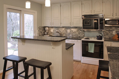 Kitchen - mid-sized traditional l-shaped light wood floor kitchen idea in DC Metro with a single-bowl sink, raised-panel cabinets, white cabinets, granite countertops, gray backsplash, glass sheet backsplash, white appliances and an island