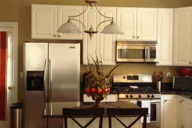 Inspiration for a mid-sized transitional l-shaped medium tone wood floor enclosed kitchen remodel in DC Metro with an undermount sink, recessed-panel cabinets, white cabinets, granite countertops, stainless steel appliances and an island