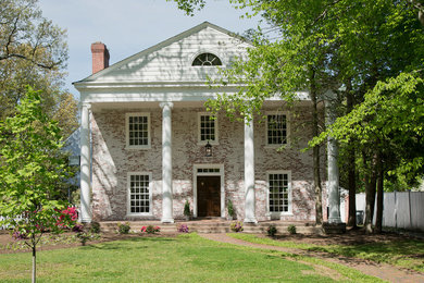 Photo of a large traditional two-storey brick white house exterior in DC Metro with a gable roof and a shingle roof.