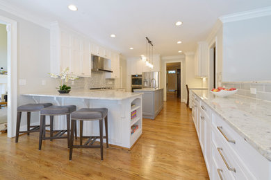 Inspiration for a large transitional u-shaped medium tone wood floor eat-in kitchen remodel in Other with an undermount sink, recessed-panel cabinets, white cabinets, granite countertops, ceramic backsplash, stainless steel appliances and an island