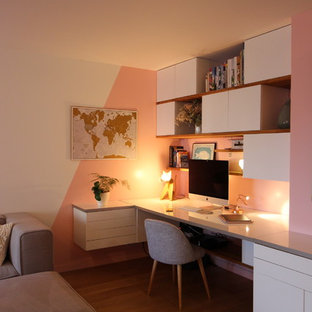 Exempel på ett litet modernt hemmabibliotek, med rosa väggar, ljust trägolv, ett inbyggt skrivbord och brunt golv