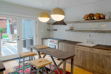 Eat-in kitchen - mid-sized rustic single-wall light wood floor eat-in kitchen idea in Philadelphia with a drop-in sink, distressed cabinets, wood countertops, white backsplash, subway tile backsplash, flat-panel cabinets, white appliances and an island