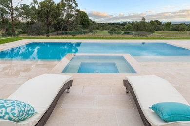 Modern backyard custom-shaped pool in Other with natural stone pavers.
