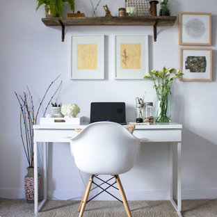 This is an example of a small modern home office and library in Toronto with white walls, carpet and a freestanding desk.