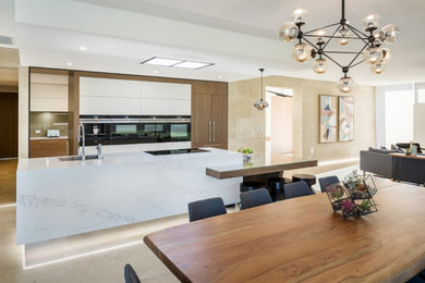 Design ideas for a large contemporary galley open plan kitchen in Perth with a single-bowl sink, flat-panel cabinets, medium wood cabinets, quartz benchtops, glass sheet splashback, black appliances, limestone floors, with island and beige floor.