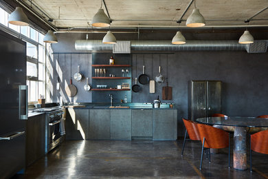 Example of a mid-sized urban l-shaped concrete floor and brown floor open concept kitchen design in Los Angeles with flat-panel cabinets, gray cabinets, granite countertops, gray backsplash, no island, black countertops, an undermount sink and stainless steel appliances