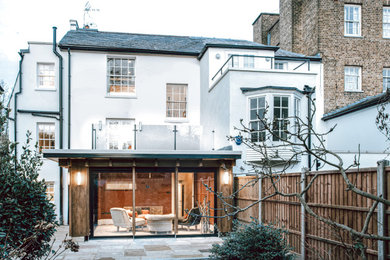 Inspiration for a mid-sized three-storey stucco white duplex exterior in London with a gable roof and a tile roof.