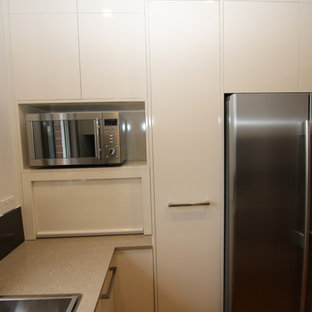 Kleine Moderne Küche ohne Insel in U-Form mit Vorratsschrank, Doppelwaschbecken, flächenbündigen Schrankfronten, beigen Schränken, Quarzwerkstein-Arbeitsplatte, Küchenrückwand in Metallic, Glasrückwand, Küchengeräten aus Edelstahl und hellem Holzboden in Sydney