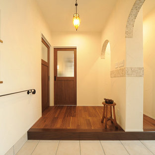 他の地域の片開きドアカントリー風おしゃれな玄関ホール (白い壁、木目調のドア) の写真