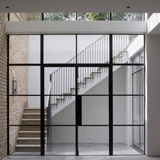 Photo of an expansive industrial look-out basement in London with beige walls, concrete flooring, a wood burning stove, a plastered fireplace surround and white floors.
