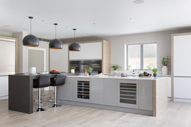 Design ideas for an expansive contemporary open plan kitchen in Surrey with an integrated sink, flat-panel cabinets, grey cabinets, quartzite benchtops, panelled appliances, porcelain floors, with island, grey floor and white benchtop.