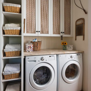 Photo of a country utility room in Dallas with recessed-panel cabinets, white cabinets, beige walls, brick flooring, a side by side washer and dryer, red floors and beige worktops.