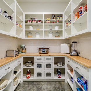 Large farmhouse kitchen pantry ideas - Large farmhouse u-shaped concrete floor and gray floor kitchen pantry photo in Jackson with a farmhouse sink, open cabinets, white cabinets, wood countertops, white backsplash, subway tile backsplash, stainless steel appliances and an island